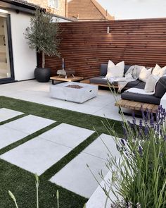 an outdoor living area with artificial grass and wooden slatted walls on the side