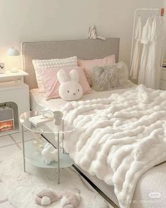 a white bed with fluffy blankets and pillows on top of it next to a night stand