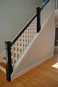 a white staircase with black handrails and wood flooring in a living room