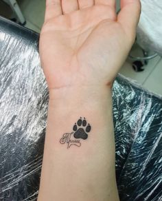 a woman's wrist with a small paw tattoo on the left side of her arm