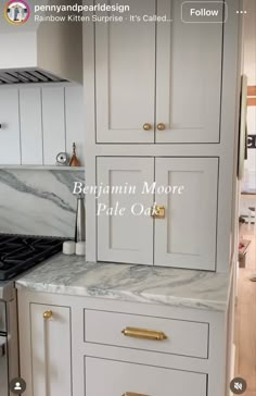 a kitchen with white cabinets and marble counter tops, including the bottom cabinet has gold handles