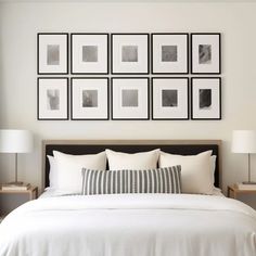 a bed with white sheets and pillows in front of pictures on the wall above it