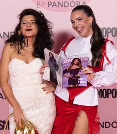 two women standing next to each other while holding magazine's covers in their hands