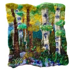 an embroidered pillow with trees and bushes on it