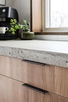 a kitchen counter top with black handles and a coffee maker in the backgrouund