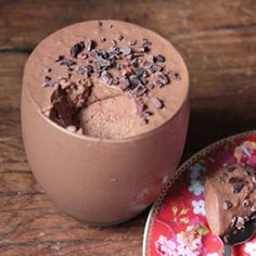 there is a chocolate dessert in the cup next to it's plate on the table