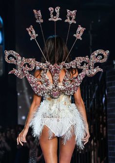 a model walks down the runway in a feathered outfit