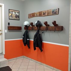 two coats and helmets are hanging on the wall