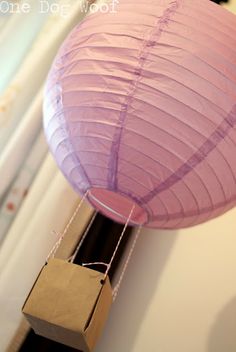 a purple paper lantern is hanging from a string on the wall next to a window