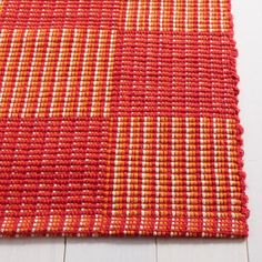 an orange and white rug on the floor with wood floors in the background, close up