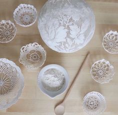 crocheted doily, bowls and spoons on a wooden table