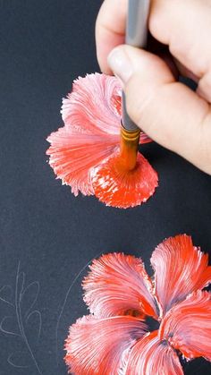 a person is drawing with colored pencils on a piece of paper that has red flowers in it