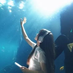 a woman wearing headphones standing in front of an aquarium