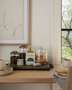 a kitchen counter with coffee, cookies and other items on it next to a window