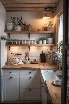 a kitchen with white cabinets and wooden shelves filled with pots, pans and other items