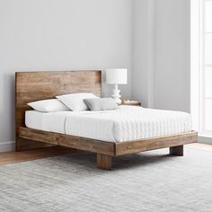 a bed sitting on top of a wooden frame in a bedroom next to a window