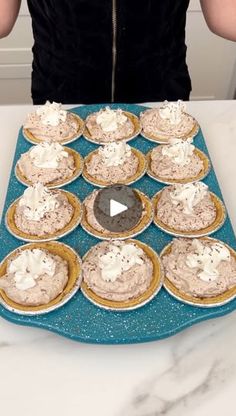 a woman standing in front of a table filled with pies and cupcakes