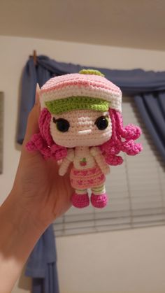 a small crocheted doll is held up to the camera