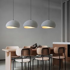 a dining room table with chairs and lights hanging from the ceiling