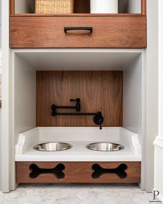 a dog's kennel with two stainless steel bowls