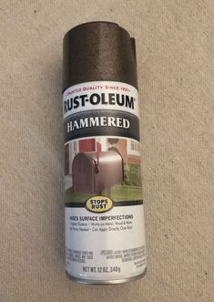 a can of rust - oleeum hammered brown paint sits on the floor next to a roll of carpet