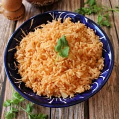 a blue and white bowl filled with rice on top of a wooden table