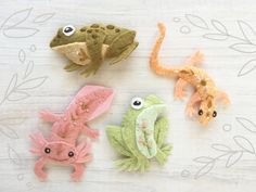 four felt geckos sitting on top of a wooden table