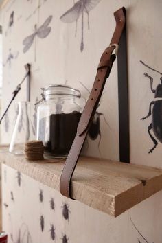 a leather belt is hanging on the wall next to some glass jars and spoons