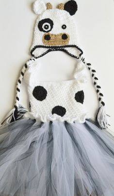 a crocheted cow hat and tutu skirt are hanging up on the wall