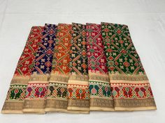 six pieces of multicolored cloth laid out on a white tablecloth covered floor