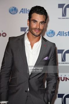 a man in a suit and white shirt posing for a photo on the red carpet