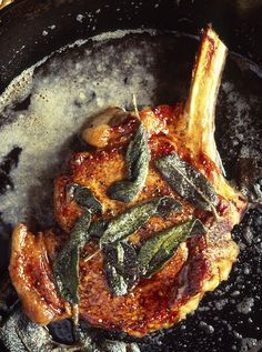 a close up of food in a pan with sauce and herbs on it, including meat