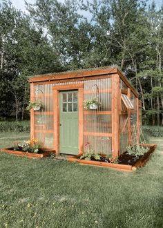 a small garden shed in the middle of some grass