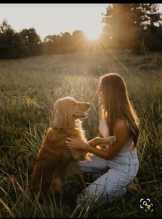 a woman is sitting in the grass with her golden retriever, who is looking into the distance