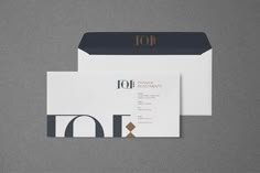 two white envelopes with black and gold foil on the front, one is open