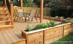 a wooden deck with chairs and plants on it