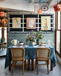 a dining room with blue table cloths and pictures on the wall above it, along with wicker chairs