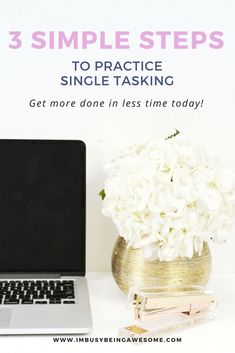 a laptop computer sitting on top of a desk next to a vase with white flowers