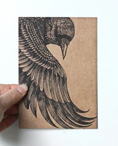 a hand holding up a piece of paper with a drawing of a bird on it