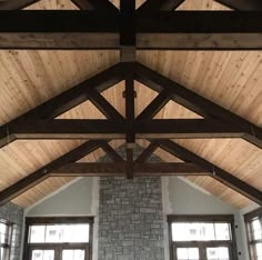 a living room filled with lots of windows next to a stone wall and wooden beams