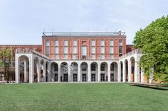 an outdoor courtyard in front of a brick building with arches and columns on the sides