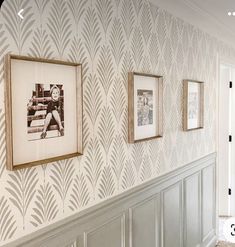 three framed photographs hang on the wall next to a hallway with white wainscoting