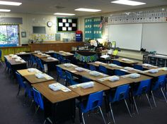 an empty classroom with blue chairs and desks