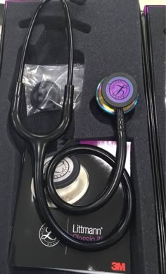 a black stethoscope sitting on top of a box filled with medical supplies