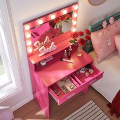 a pink vanity table with lights on it