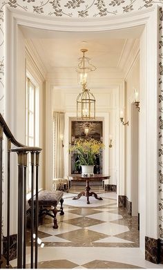 an elegant foyer with chandelier, marble floor and checkerboard pattern on the walls