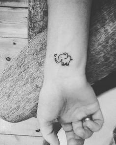 a small elephant tattoo on the left inner wrist is shown in this black and white photo