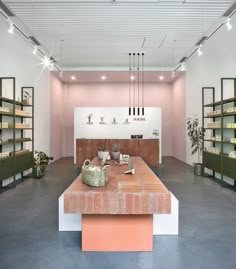 an empty room with shelves and plants on the tables in front of it is a pink wall