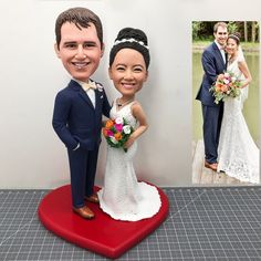 a wedding cake topper with a bride and groom standing on a heart shaped base