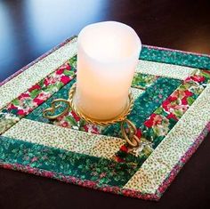 a lit candle sitting on top of a quilted placemat